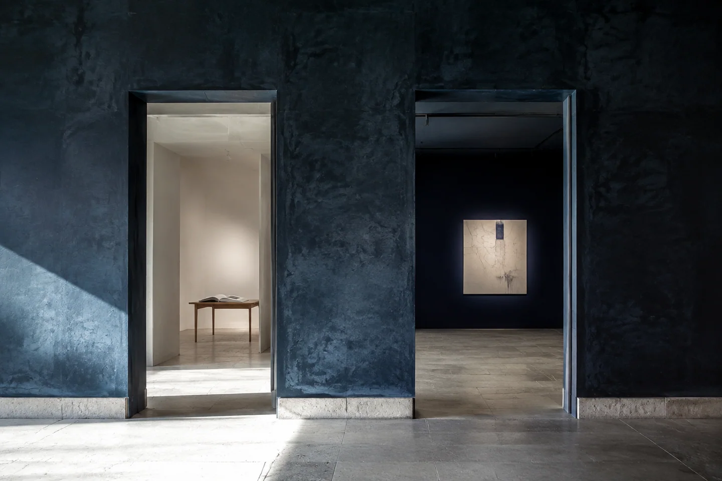 Composition d’intention : deux portes adjacentes relient une salle de lecture claire et une salle d’exposition bleu nuit.